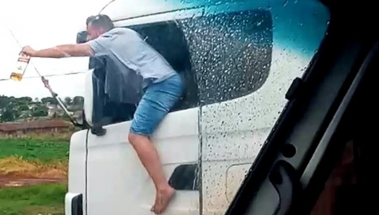 Caminhoneiro é flagrado com corpo para fora de veículo com garrafa de bebida